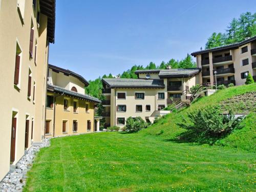 a building with a grassy yard next to some buildings at Apartment Residenza Chesa Margun 59-6 by Interhome in Surlej