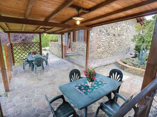 een patio met een tafel en stoelen en een stenen muur bij Apartment Vecchio Cigliere - TER106 by Interhome in Laiatico