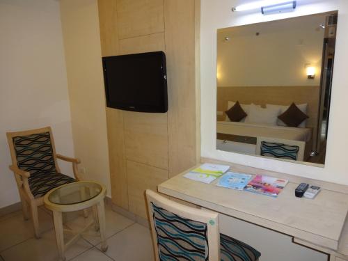 a room with a table and a television and a bed at Hotel Southern Grand in Vijayawāda