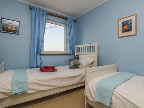 a blue bedroom with two beds and a window at Away West in St. Just