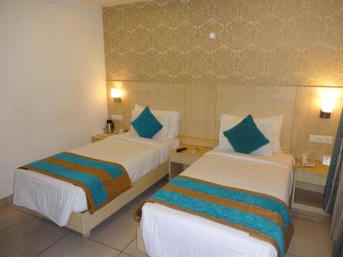 a hotel room with two beds with blue pillows at Hotel Southern Grand in Vijayawāda