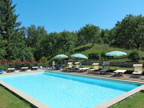 una piscina con sedie a sdraio e ombrelloni accanto ad essa di Apartment Le Bore-1 by Interhome a Sassi