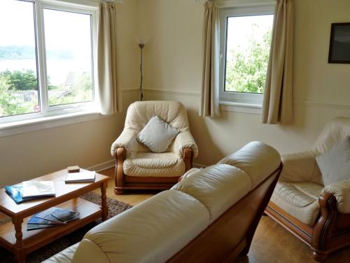 a living room with a couch and chairs and windows at Holiday Home Ewan's by Interhome in Staffin