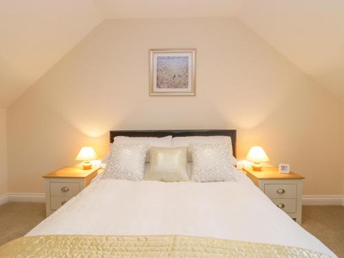 a bedroom with a large bed with two lamps on tables at The Donkey Shed in Sherborne