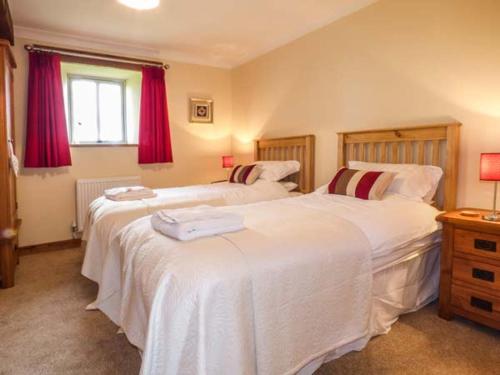 two beds in a bedroom with red curtains at Ty Buddug in Llandegla