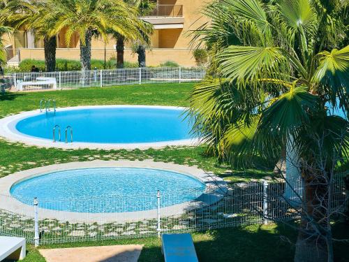 a large blue swimming pool in a yard with palm trees at Apartment Marmara-4 by Interhome in Jávea