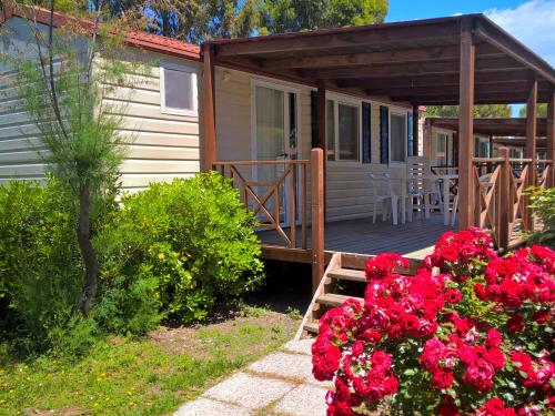 una casa con un portico con fiori rossi di fronte di Holiday Home Cecina Mare-10 by Interhome a Marina di Cecina