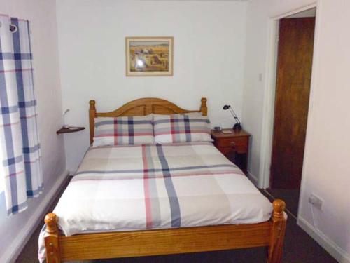 a bedroom with a wooden bed with a striped pillow at Harley Apartment in Bishops Castle