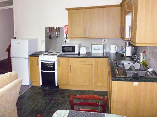 a kitchen with wooden cabinets and white appliances at Harley Apartment in Bishops Castle