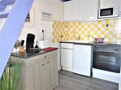 une cuisine avec des armoires blanches et un appareil noir dans l'établissement Apartment Les Capounades-2 by Interhome, à Narbonne-Plage