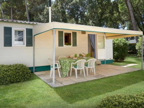 una piccola roulotte con tavolo e sedie in cortile di Holiday Home Maxi Caravan Escale by Interhome a Baia Domizia