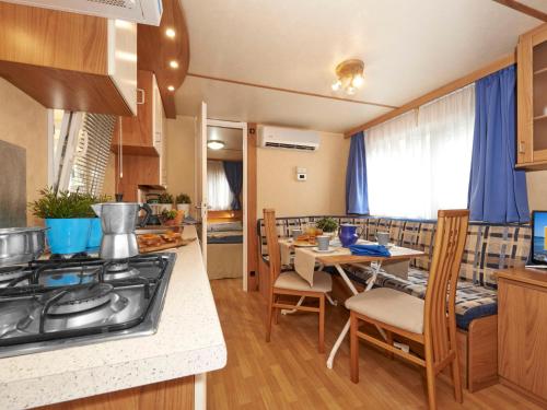 cocina y sala de estar con mesa y fogones en Holiday Home Maxi Caravan Deluxe by Interhome, en Baia Domizia