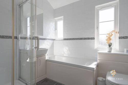 biała łazienka z wanną i umywalką w obiekcie Conker Tree House w mieście Great Staughton
