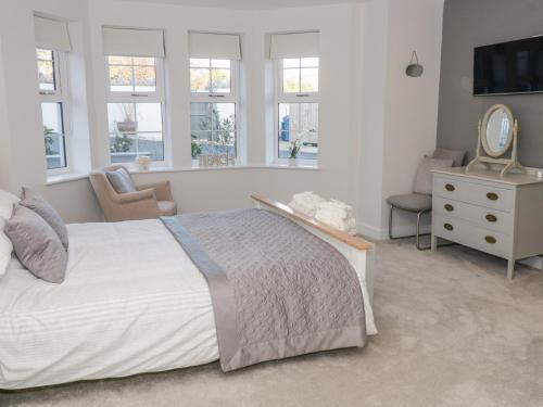 1 dormitorio con cama, espejo y silla en Hafan Traeth Beach Haven en Benllech