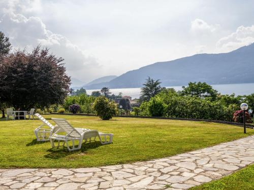 deux chaises blanches assises sur l'herbe près de l'eau dans l'établissement Apartment Malpensata by Interhome, à Porto Valtravaglia