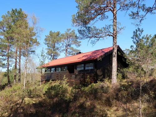 a log cabin in the woods with a red roof at Holiday Home Sandvikfjellet by Interhome in Nyttingsnes