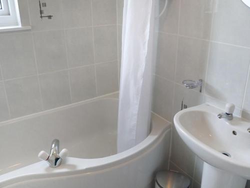 a white bathroom with a tub and a sink at Holiday Home Alan's House by Interhome in Staffin