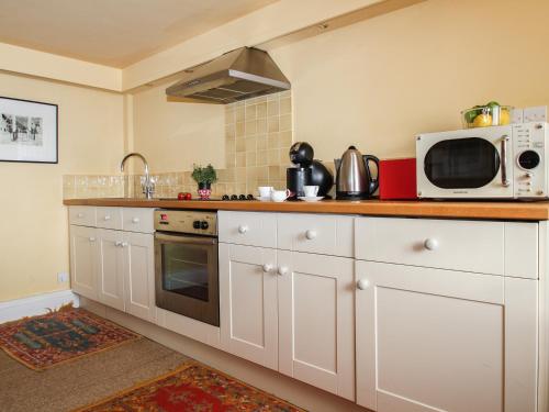 a kitchen with white cabinets and a microwave at The Slipway in Penzance