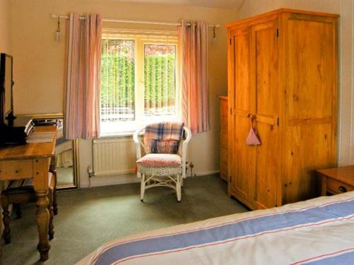 a bedroom with a bed and a chair and a window at Waterloo Cottage Annexe in Ruswarp