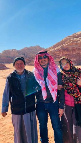 a group of three people standing in the desert at Shakria Bedouin Life Camp in Wadi Rum