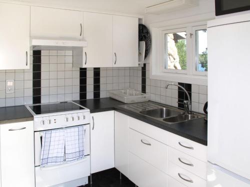 una cocina con armarios blancos y fregadero en Holiday Home Munkhalla Utsikten - B, en Asarum
