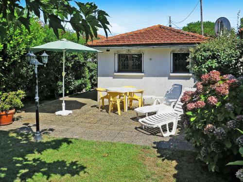 a patio with a table and chairs and an umbrella at Holiday Home La Poste by Interhome in Mimizan-Plage