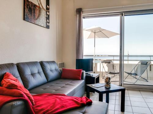 - un salon avec un canapé et un balcon avec un parasol dans l'établissement Apartment Grand Pavois-2 by Interhome, à Mimizan-Plage