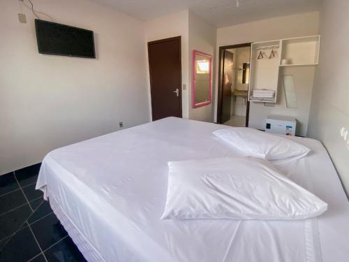 a white bed with white sheets in a room at GUINZA in Balneário Camboriú