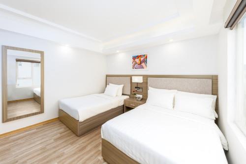a hotel room with two beds and a mirror at Golden Rose Hotel in Da Nang