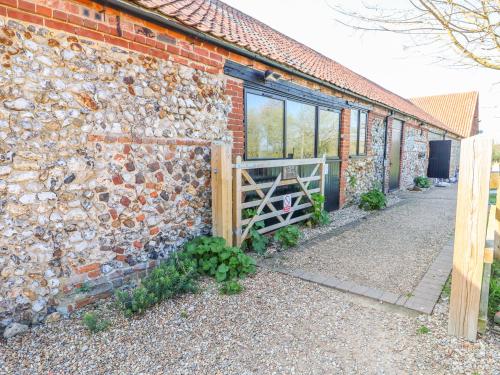 a brick building with a wooden fence next to it at The Dairy Barn in Fakenham