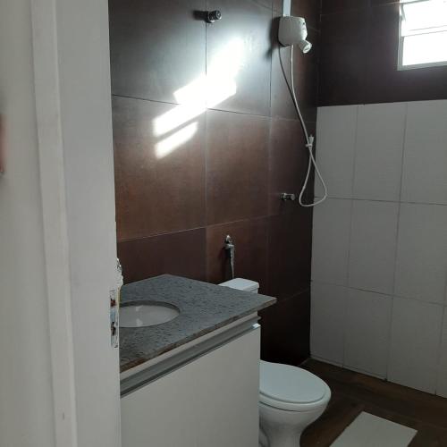 a bathroom with a toilet and a sink and a light at Casa Vitória em barra de jacuipe in Campos