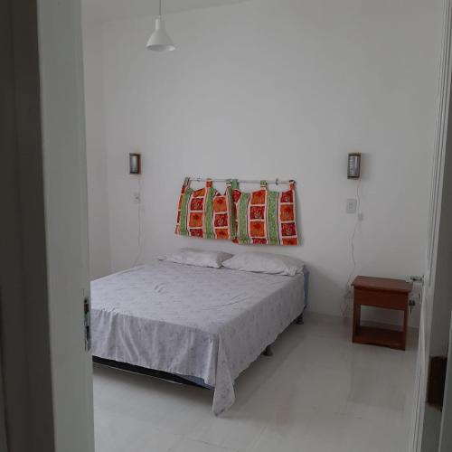 a small white bedroom with a bed with a blanket at Casa Vitória em barra de jacuipe in Campos