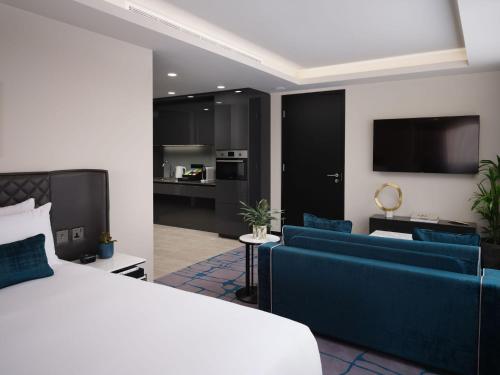 a bedroom with a bed and a living room with blue furniture at Dao by Dorsett West London in London