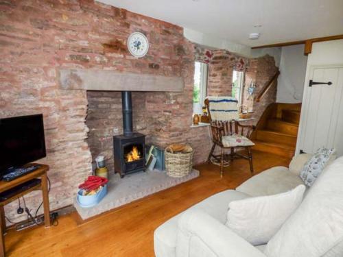 a living room with a brick wall with a fireplace at Rose Cottage in Monmouth