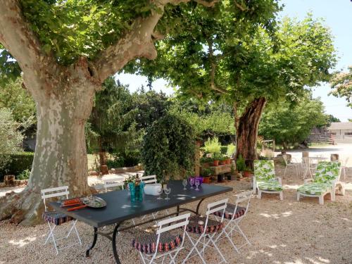 une table et des chaises noires sous un arbre dans l'établissement Holiday Home Mas de la Gourmette by Interhome, à Châteaurenard