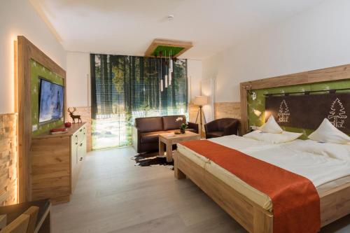 a bedroom with a large bed and a television at Wellnesshotel Tanne in Baiersbronn