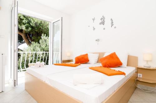 a white bed with orange pillows in a room with a window at Guest House Daniela in Mlini