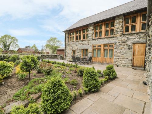 an exterior view of a stone house with a patio at Hendoll Barn in Fairbourne