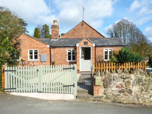 a brick house with a white picket fence at Kitts Cottage in Malvern Wells