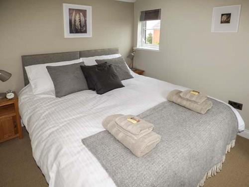 een groot wit bed met 2 handdoeken erop bij Kitts Cottage in Malvern Wells