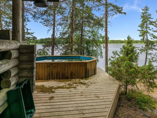 un bain à remous sur une terrasse en bois à côté d'un lac dans l'établissement Holiday Home Elimäki by Interhome, à Heinjoki
