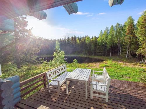 dois bancos brancos em um deck com uma mesa em Holiday Home Päivärinne by Interhome em Mäkisauru