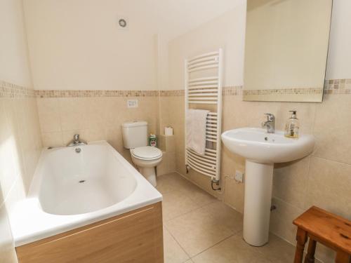 a bathroom with a tub and a sink and a toilet at Bryn Howell Stables in Trevor