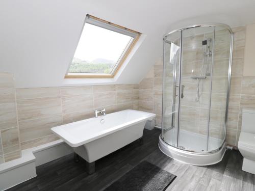 La salle de bains est pourvue d'une baignoire, d'une douche et d'un lavabo. dans l'établissement Station Apartment, à Llanberis