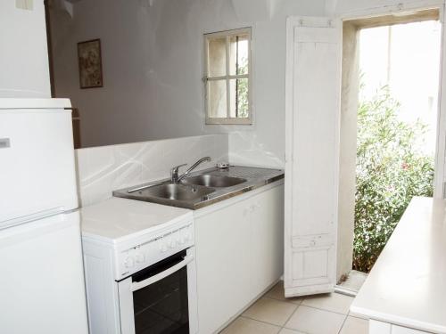 een witte keuken met een wastafel en een raam bij Holiday Home La Cadièrienne by Interhome in La Cadière-dʼAzur