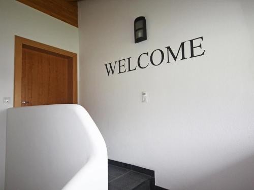 a white bathroom with a welcome sign on the wall at Apartment Lanner by Interhome in Innsbruck
