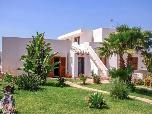 una casa blanca con palmeras en un patio en Apartment La Rosa-4 by Interhome, en Plemmirio