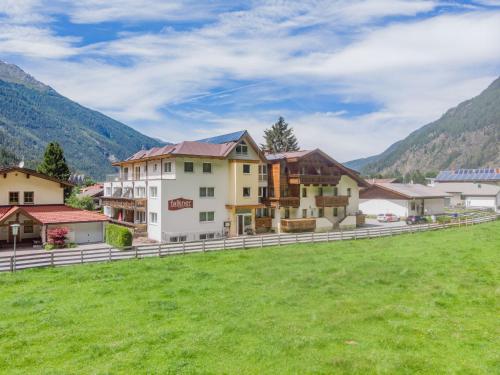 a group of buildings in a field with mountains at Apartment Falkner-12 by Interhome in Oberlängenfeld