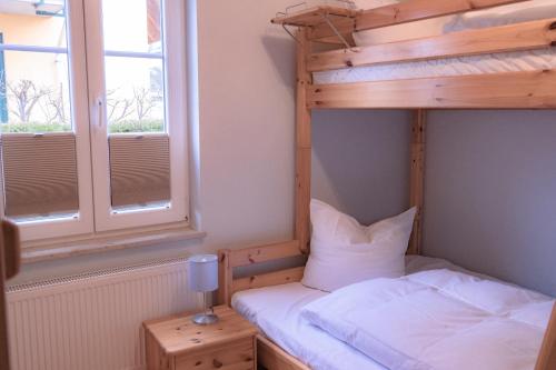 a bedroom with a bunk bed and a window at Haus Sabine - EG in Groß Kirr