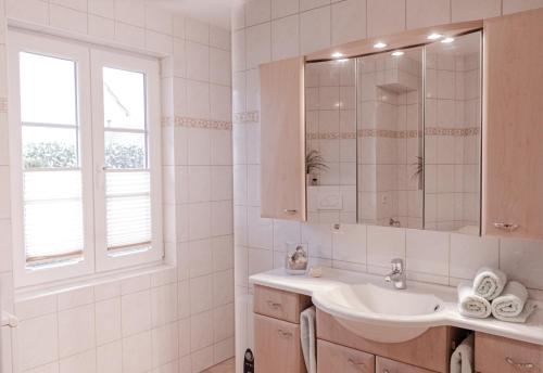 a white bathroom with a sink and a window at Haus Sabine - EG in Groß Kirr
